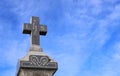 Cross on top of old gravestone with blue sky in background Royalty Free Stock Photo