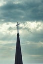 Cross up on the top of church steeple against cloudy sky in background Royalty Free Stock Photo