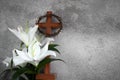 Cross with white lilies and crown of thorns on grey background. Christianity Easter concept. Royalty Free Stock Photo