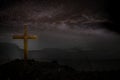 Cross wooden raised to the glory of God, Jesus Christ. Night light lighting a fire on a background of stones under the stars of th