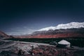 NomadÃ¢â¬â¢s tent, snow-capped mountains in the distance, blue sky and red rock mountains, a grassland in the valley