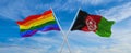 crossed flags of lgbt and Afghanistan flag waving in the wind at cloudy sky. Freedom and love concept. Pride month. activism,
