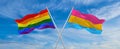 crossed flags of lgbt and Pansexuality Pride flag waving in the wind at cloudy sky. Freedom and love concept. Pride month.