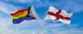crossed flags of progress lgbt pride and England flag waving in the wind at cloudy sky. Freedom and love concept. Pride month.