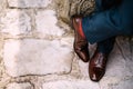 Crossed legs of a man in blue pants, red socks and brown shoes standing on the stone road, top view Royalty Free Stock Photo