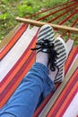 Crossed legs in a striped hammock, wearing jeans and cloth shoes Royalty Free Stock Photo