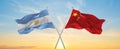 crossed national flags of Argentine and china flag waving in wind at cloudy sky. Symbolizing relationship, dialog, travelling Royalty Free Stock Photo