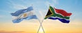 crossed national flags of Argentine and South Africa flag waving in wind at cloudy sky. Symbolizing relationship, dialog, Royalty Free Stock Photo