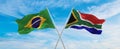 crossed national flags of Brazil and South Africa flag waving in the wind at cloudy sky. Symbolizing relationship, dialog, Royalty Free Stock Photo