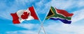 crossed national flags of Canada and South Africa flag waving in the wind at cloudy sky. Symbolizing relationship, dialog, Royalty Free Stock Photo
