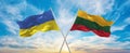 crossed national flags of Ukraine and LITHUANIA flag waving in wind at cloudy sky. Symbolizing relationship, dialog, travelling