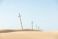 Crosses line in sand desert. Christian symbol of faith and hope. Old cross-shaped pillars on sky background. Ancient