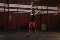 Crossfit woman holding a kettlebell overhead and smiling while crossfit training at the gym