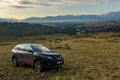 Crossover Nissan X-TRAIL on the hillside in Kurai steppe against the backdrop of the North Chuy ridge at dawn. Royalty Free Stock Photo