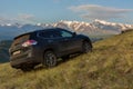 Crossover Nissan X-TRAIL on the hillside in Kurai steppe against the backdrop of the North Chuy ridge at dawn.