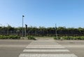 Crosswalk with a pedestrian traffic light at the end. Bike path and fence with hedge behind. No people. Royalty Free Stock Photo