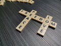 Crossword freedom peace love made from square letter tiles against black background.