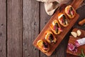 Crostini appetizer board with baked brie, sausage and pickles, top view serving scene over rustic wood with copy space