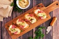 Crostini appetizers with brie cheese, salami and artichokes, above view on a serving board against rustic wood Royalty Free Stock Photo