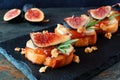 Crostini appetizers with figs, brie cheese and walnuts, close up on a slate serving board Royalty Free Stock Photo