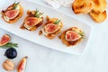 Crostini appetizers with figs, brie cheese and nuts, overhead view on plate with a marble background Royalty Free Stock Photo