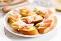 Crostini with cheese, sliced pear and prosciutto on white plate