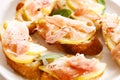 Crostini with cheese, sliced pear and prosciutto on white plate
