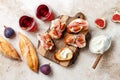 Crostini with prosciutto, cream cheese and figs on wooden board. Appetizers, antipasti snacks and red wine in glasses. Royalty Free Stock Photo