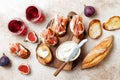 Crostini with prosciutto, cream cheese and figs on wooden board. Appetizers, antipasti snacks and red wine in glasses. Royalty Free Stock Photo