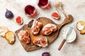 Crostini with prosciutto, cream cheese and figs on wooden board. Appetizers, antipasti snacks and red wine in glasses. Royalty Free Stock Photo