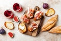 Crostini with prosciutto, cream cheese and figs on wooden board. Appetizers, antipasti snacks and red wine in glasses. Royalty Free Stock Photo
