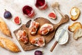 Crostini with prosciutto, cream cheese and figs on wooden board. Appetizers, antipasti snacks and red wine in glasses. Royalty Free Stock Photo