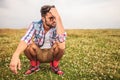 Crouched casual man in a grass field thinking Royalty Free Stock Photo