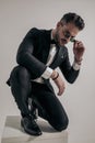 Crouching businessman arranging sunglasses and looking down Royalty Free Stock Photo