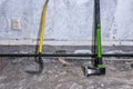 Crowbar and wood splitting maul stand at concrete wall on demolished room floor, close up view