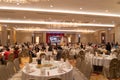 Crowd of Asian people in wedding ceremony with stage in convention hall. Celebration