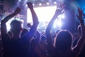 Crowd of audience with hands raised at a music festival. Lights streaming down from above the stage Royalty Free Stock Photo