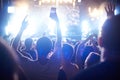 Crowd of audience with hands raised at a music festival. Lights streaming down from above the stage Royalty Free Stock Photo