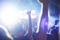 Crowd of audience with hands raised at a music festival. Lights streaming down from above the stage Royalty Free Stock Photo