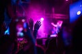 Crowd of audience with hands raised at a music festival. Lights streaming down from above the stage Royalty Free Stock Photo