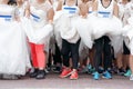 Crowd of brides prepares for their race by lining up in front of starting line, in which groom will serve as their goal. It`s a Royalty Free Stock Photo