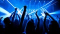 crowd dancing with neon blue lasers. People dancing at party with hands up. Silhouette crowd rejoices under bright stage lights at Royalty Free Stock Photo