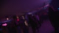 Crowd dancing under colorful spotlights and lasers, captured in defocused.