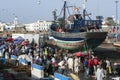 A crowd gathers along the dock of the fishing port in Essaouira in Morocco in the late afternoon.