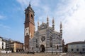 Crowd of people ambling past the towering Monza Cathedral on a sunny day. Italy.