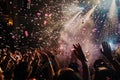 A crowd of people filled with excitement as confetti falls during a lively concert event, A burst of confetti rains down on the Royalty Free Stock Photo