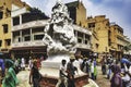Crowd of people gathered around an ornate statue in the middle of a street of Amritsar