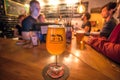 Crowd of people inside the bar with danish beer by Mikkeller brewery and designed glass