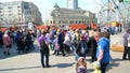 A crowd of people moving fussily against a column of watering cars.