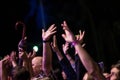 Crowd of people with their hands up during the rock concert on dark background